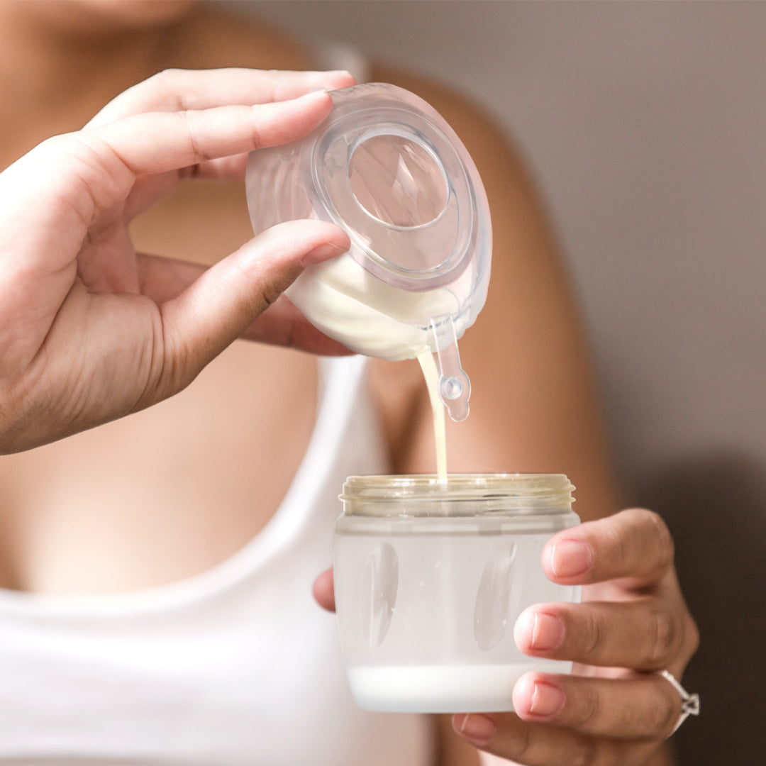 Pouring expressed milk from Haakaa Shell Wearable Pump to a Haakaa Gen. 3 Silicone Storage Container